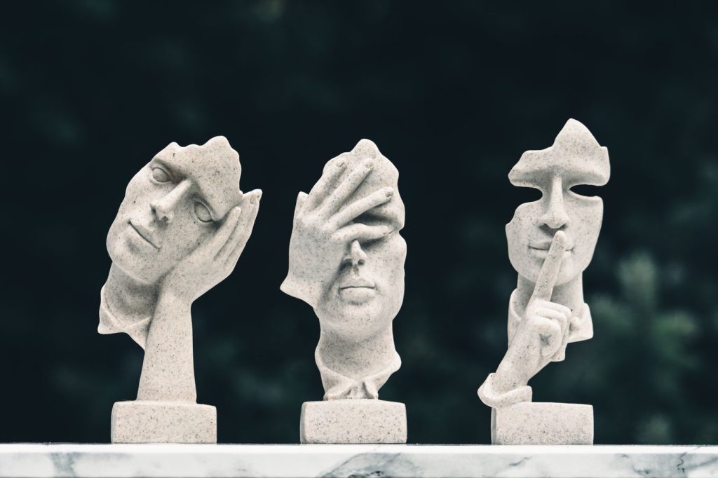 Three abstract carved faces on pedestals