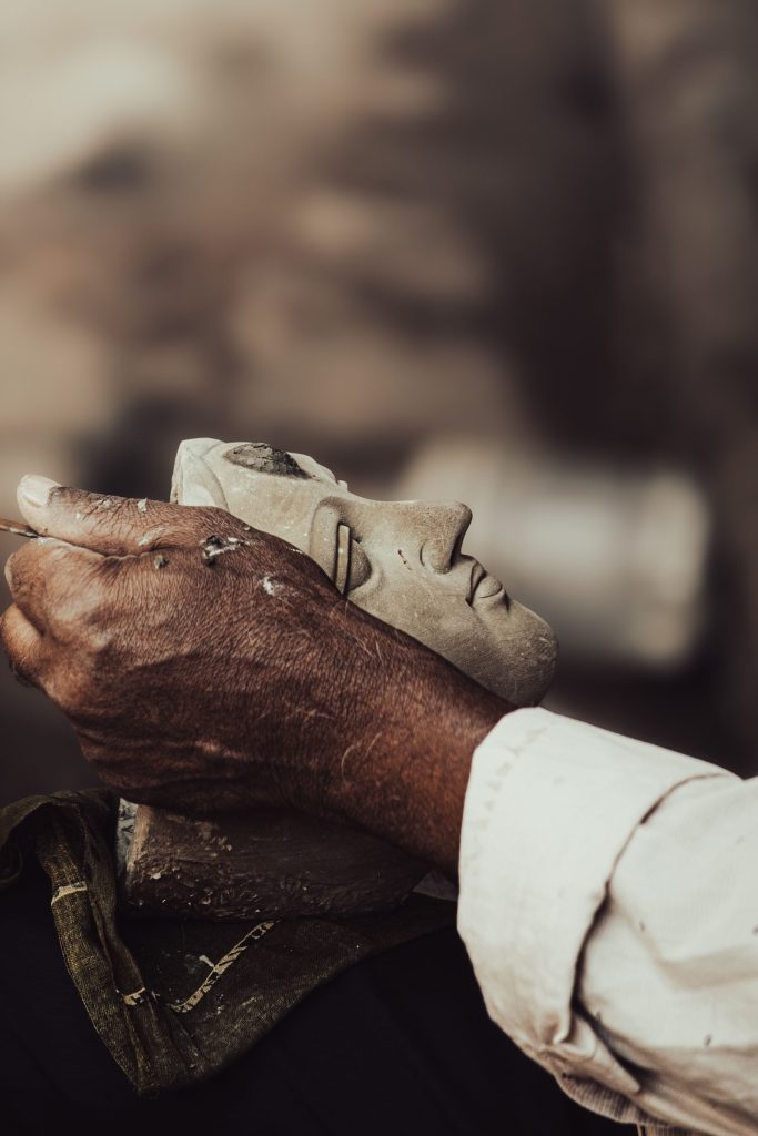 An artisan's hands carving fine detail into stone