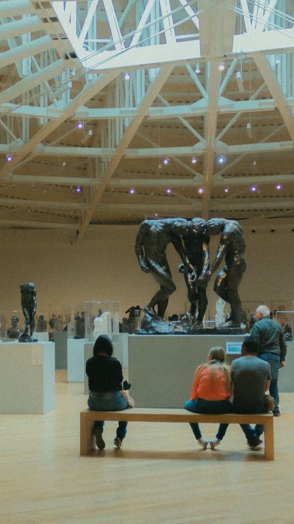 Visitors walking among sculptures in a bright exhibition hall