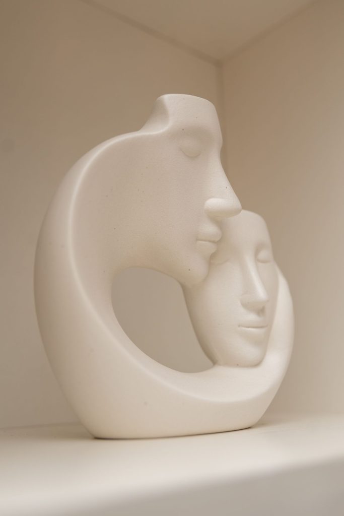 Smooth pale sculpture of two faces in an embrace